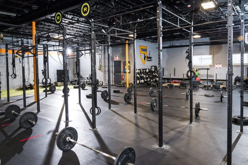 A CrossFit gym is set up for an event with barbells on the floor