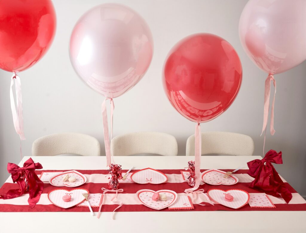 Pink and red balloons and heart shaped plates on red tablecloth for Galentine's decorations