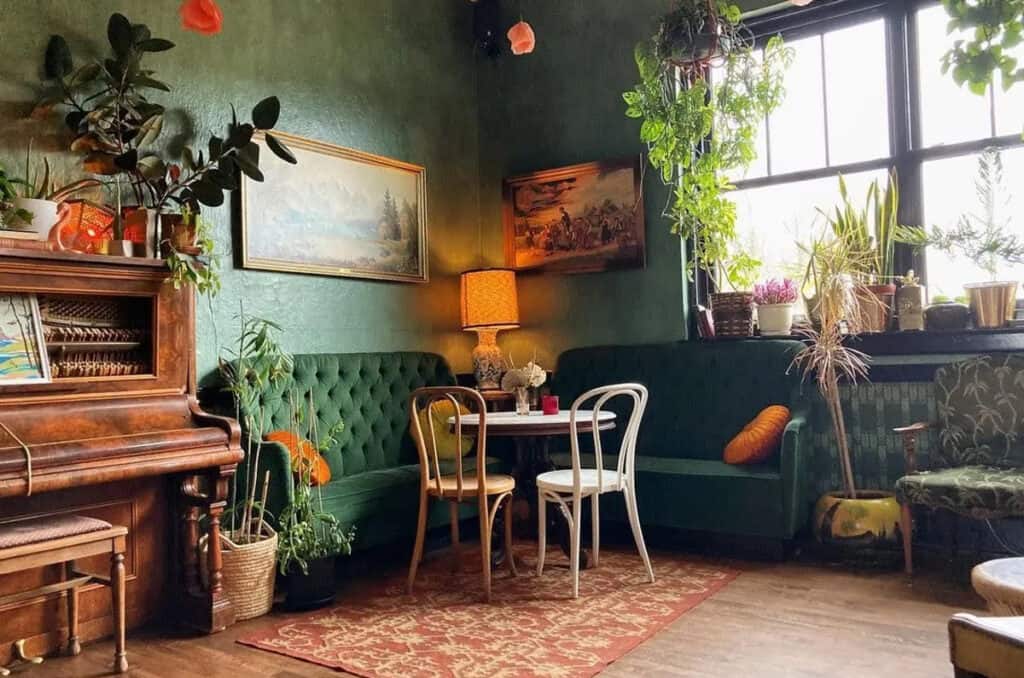 A bohemian sitting area with green sofas and white chairs