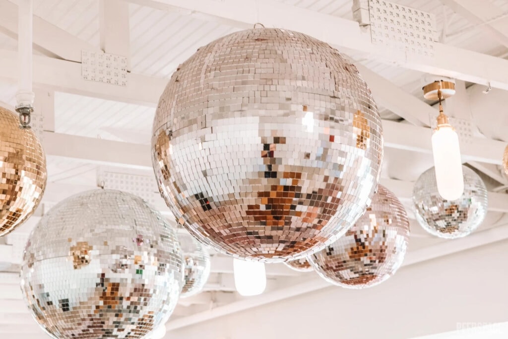 Metallic disco balls hang from a white ceiling