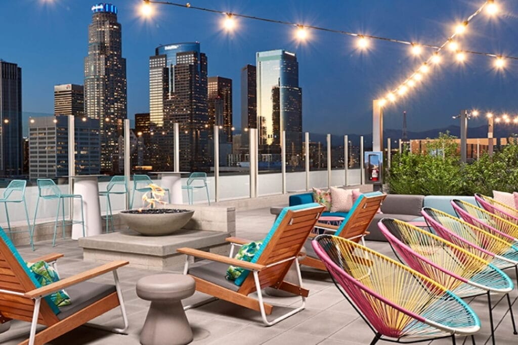 Colorful chairs and seating areas on a rooftop with downtown Los Angeles views