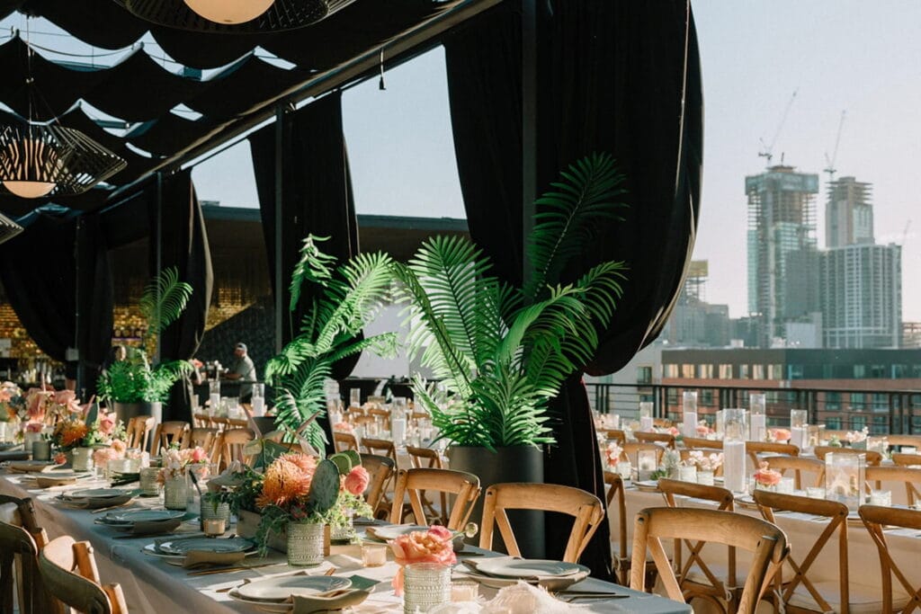 Rooftop space set up for wedding reception with greenery and pink flowers