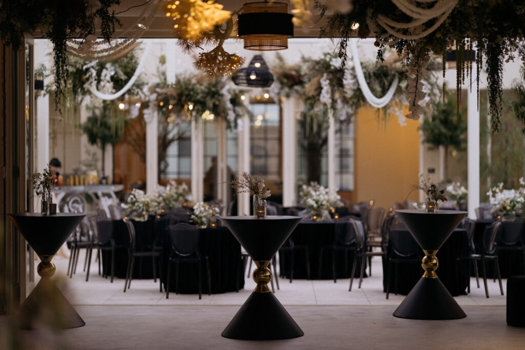 High top tables sit inside a doorway to a courtyard full of of reception tables
