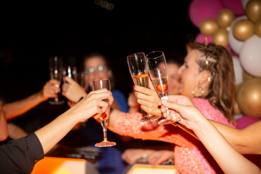 Group of people toasting champagne at a woman's birthday party with balloons