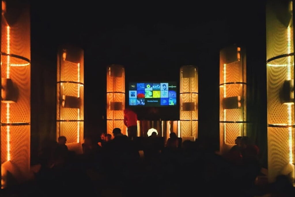 People sit in dimly-lit room at an immersive listening experience