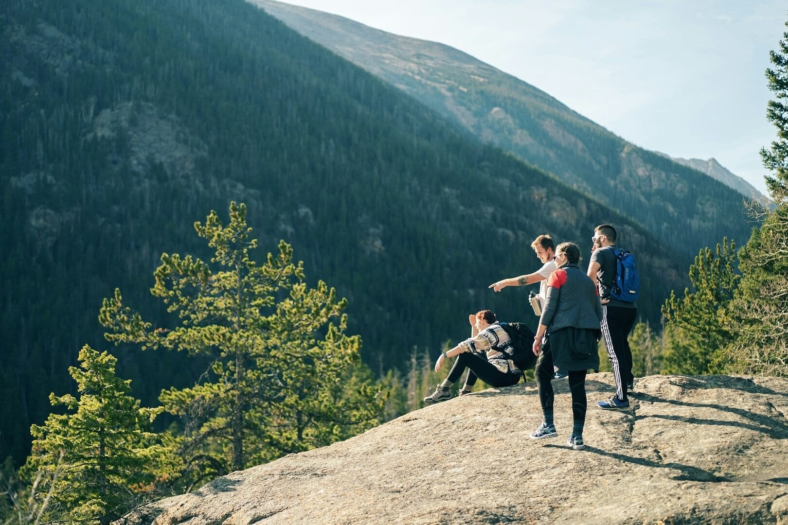 Group of four friends hiking and pointing at an overlook for brother birthday idea