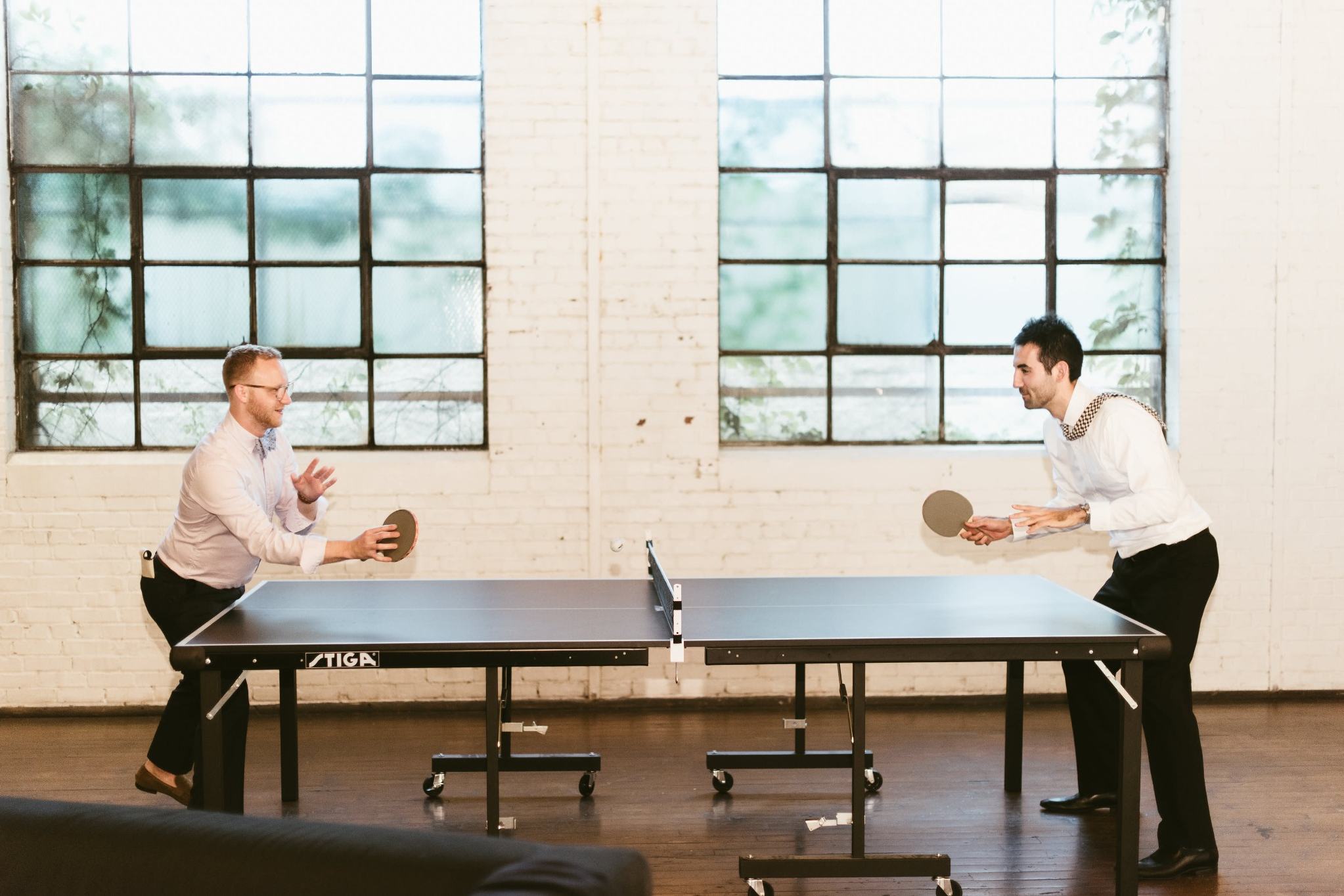 Two men playing table tennis in a modern Atlanta event venue