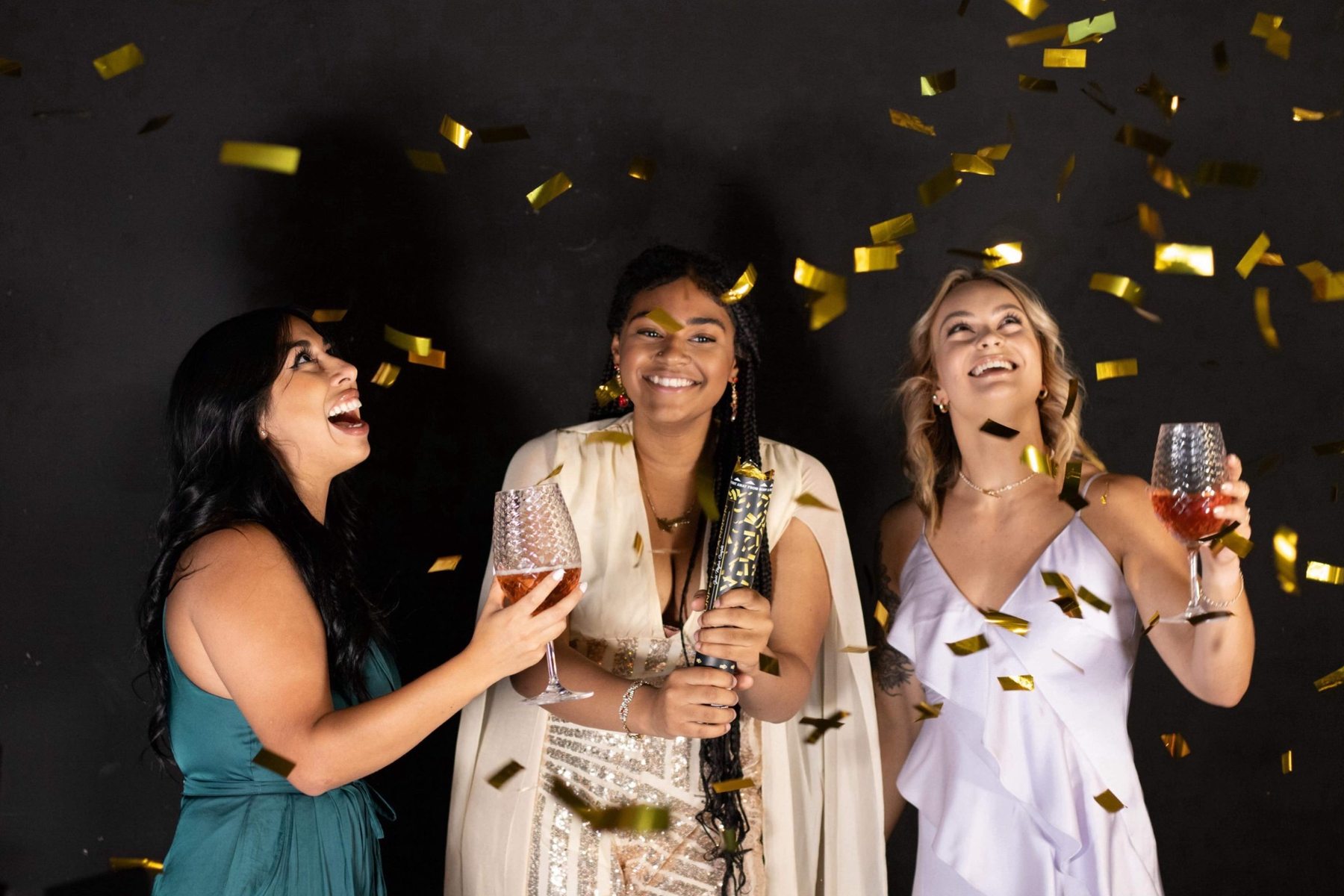 Three women celebrating with confetti and champagne at a Colorado event