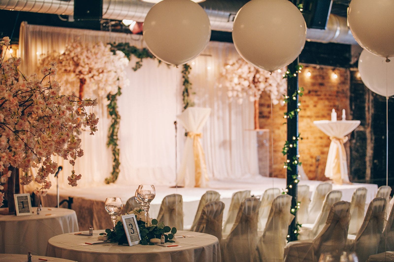 Gold Coast celebration venue with round tables, balloons, and stage décor