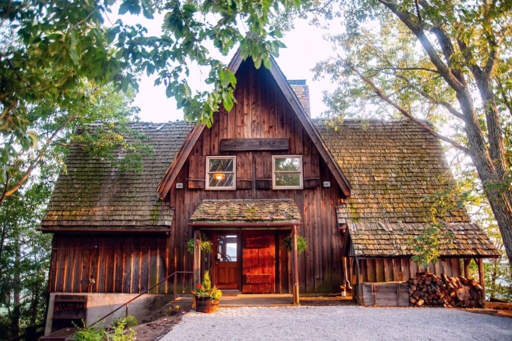 Exterior of a wood cabin with a red front door in the woods of Kentucky