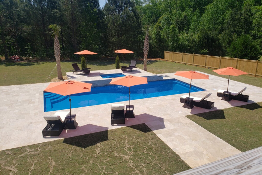 a backyard with a large pool and lounge chairs