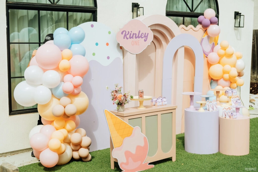 Pastel balloons and ice cream signs decorate a first birthday celebration