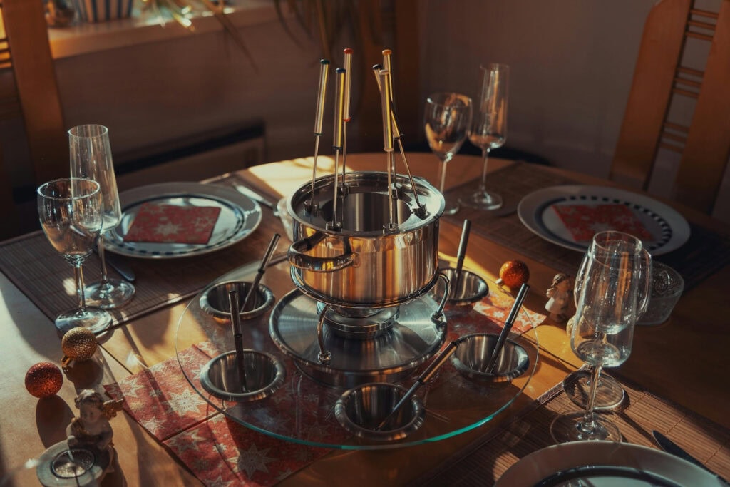 A classic fondue set sits at the center of a set table