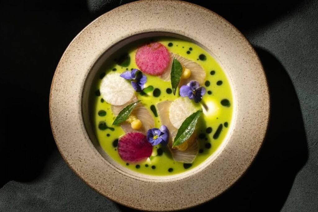 Overhead shot of a bowl of brightly colored foods and edible flowers