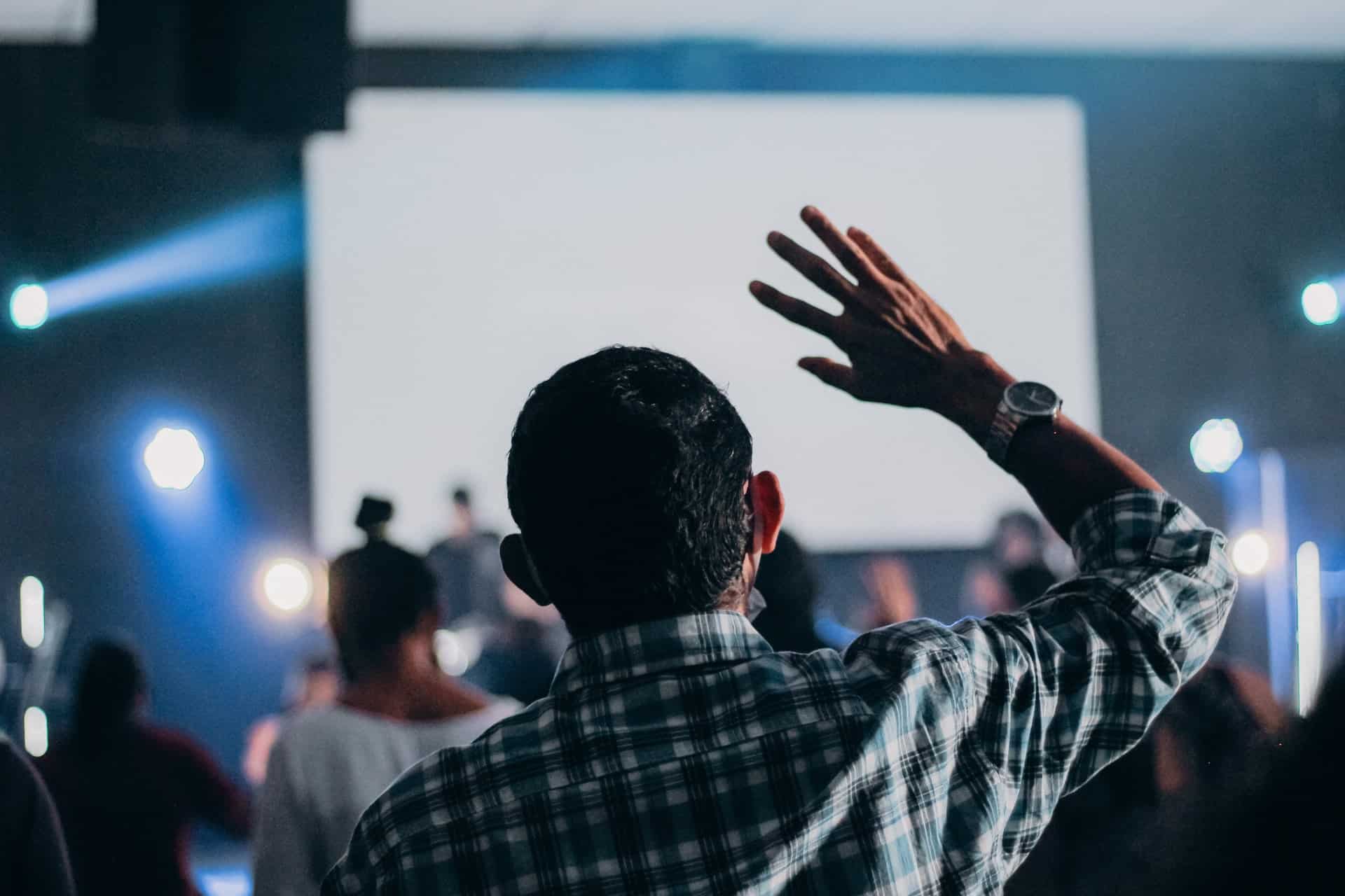 man raising his hand at conference