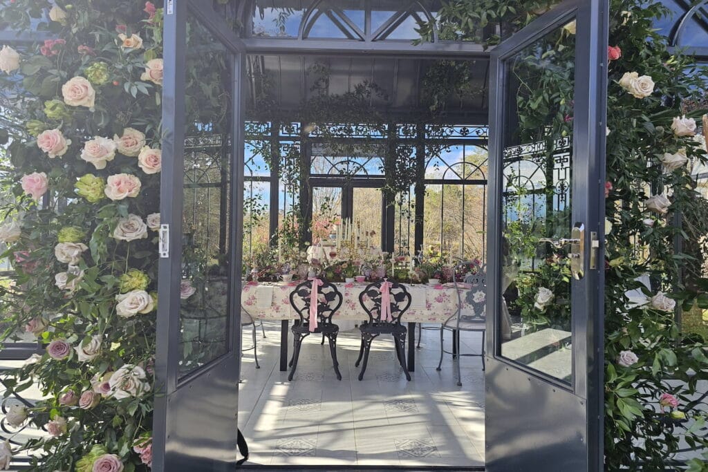 An romantic greenhouse is ornately decorated with dramatic florals and linens