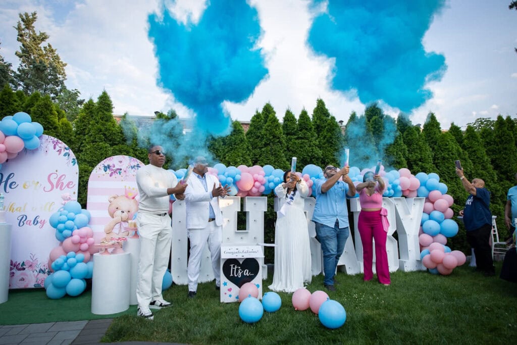 Family members learn the gender of their coming baby by way of blue smoke bombs at a reveal event