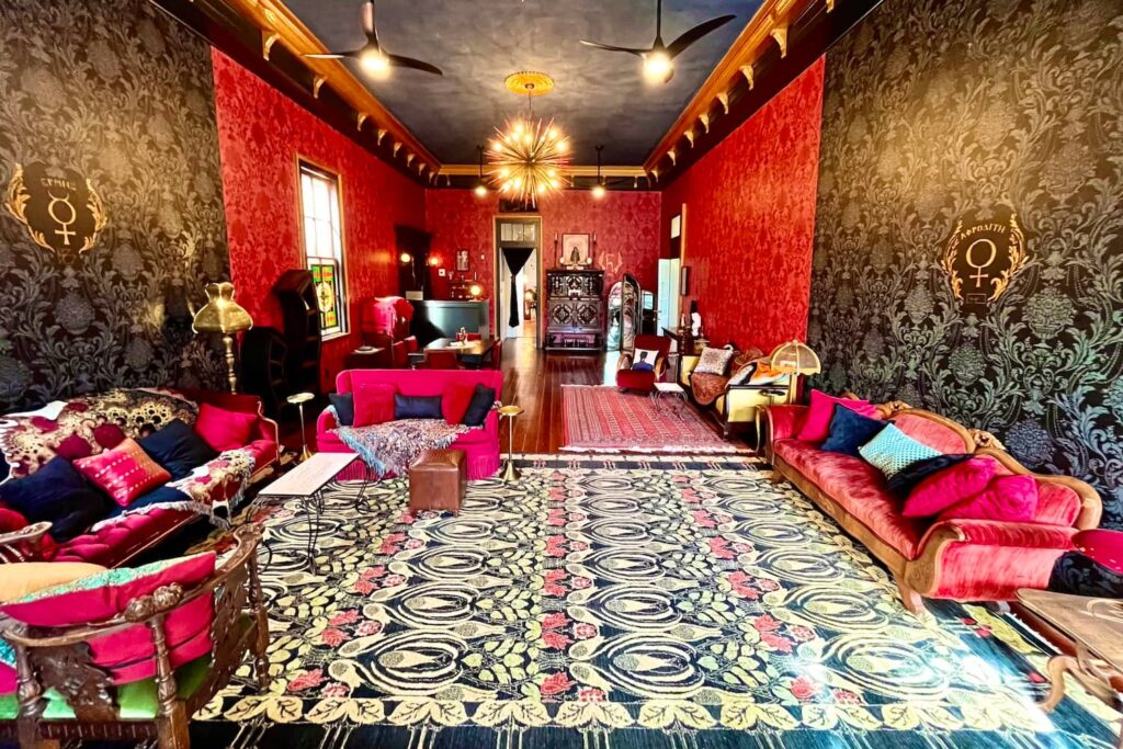 A grand living room in New Orleans with black and red walls, red velvet couches, and black accents