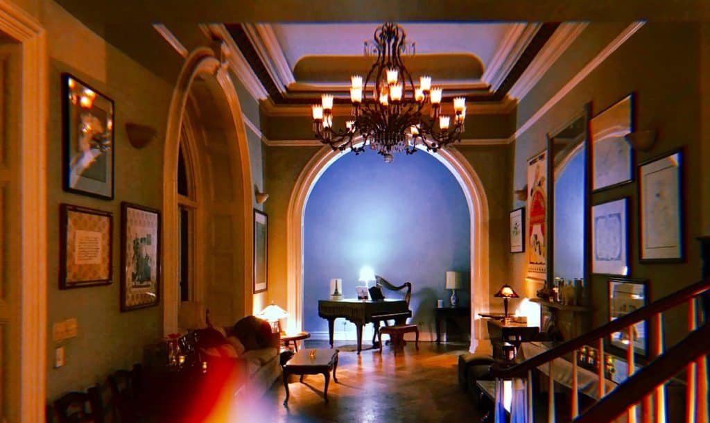 A hallway of a stately mansion that leads to a room with a piano