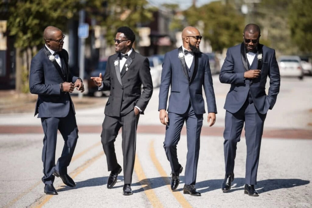 Groomsmen walk together down a street in the sunshine