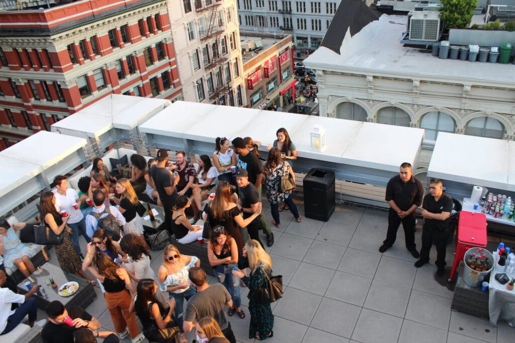 A group gathers on a city rooftop for cocktails