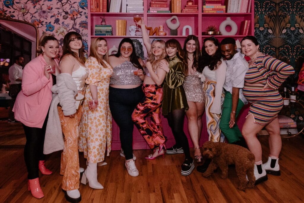 A group of friends in a pink venue space pose together for the camera