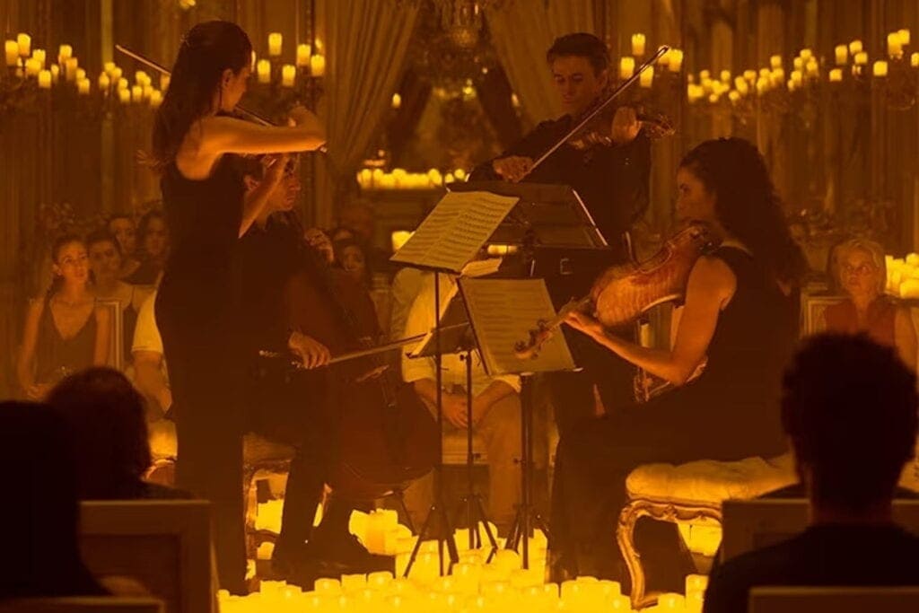 A string quartet plays to a crowd illuminated by candlelight