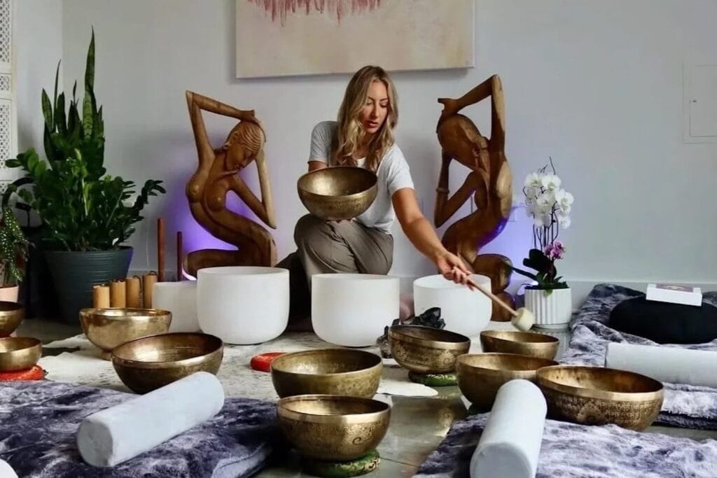 A woman performs a sound bath in a brightly lit room