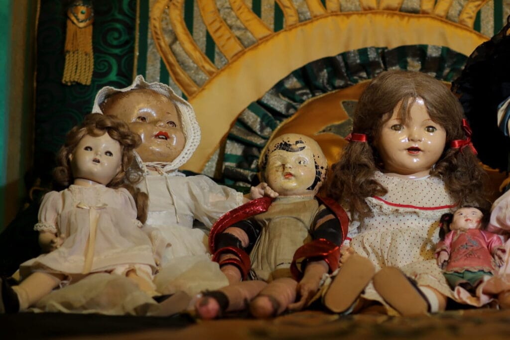 Creepy dolls sit in a row on a shelf