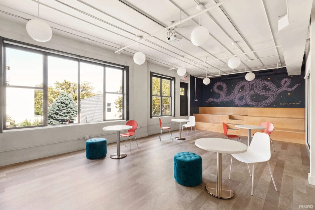 Modern furniture, wooden bleachers and a mural of a snake decorate a small, bright meeting space