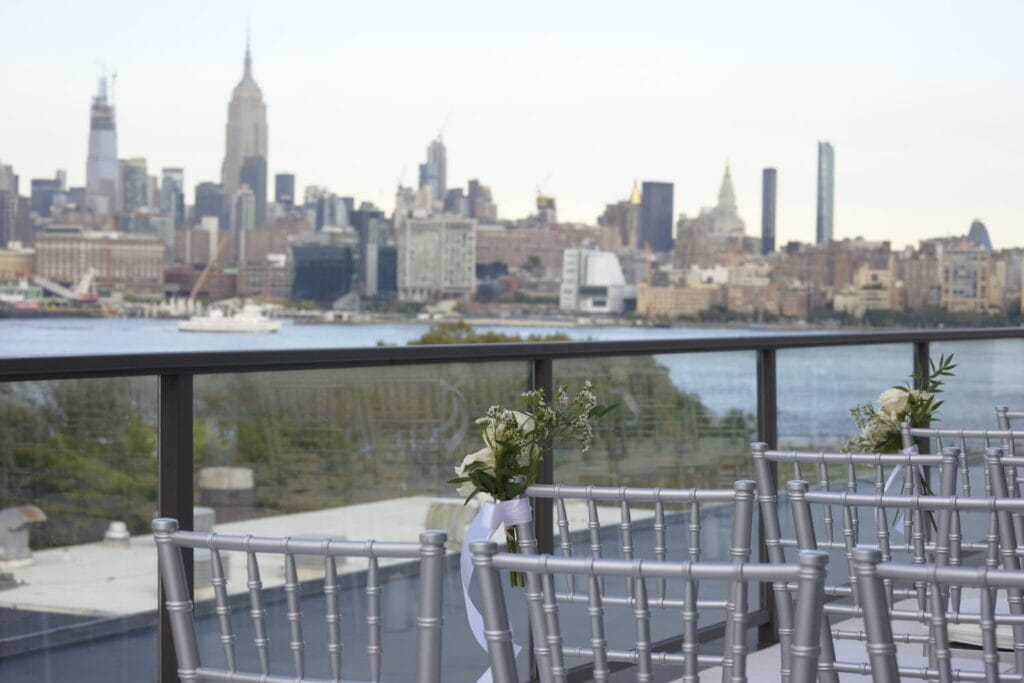 An outside terrace in Hoboken set up for a wedding ceremony with New York City views