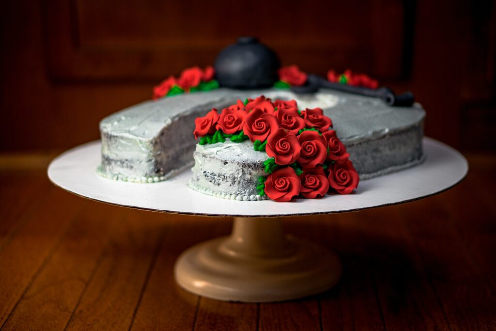 A horseshoe cake sits on a cake plate with red rose icing decorations
