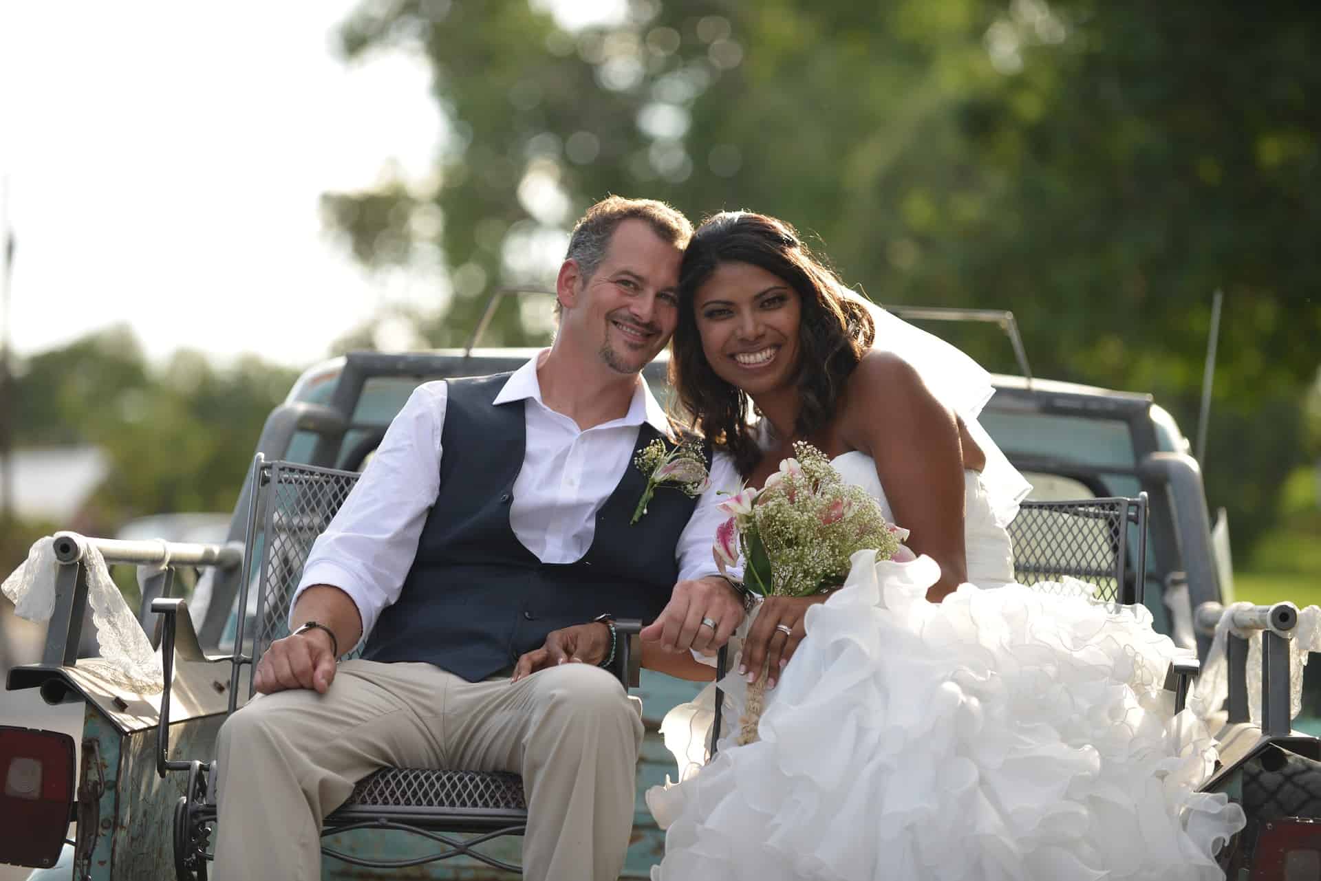 bride and groom sitting in back of pickup truck