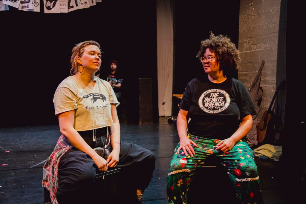 Two people sit on stage in dialogue