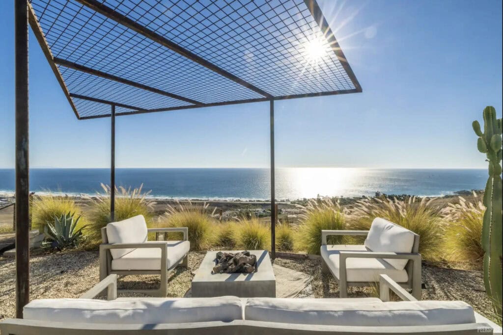 Beachfront backyard with sun shining brightly above awning that covers patio furniture
