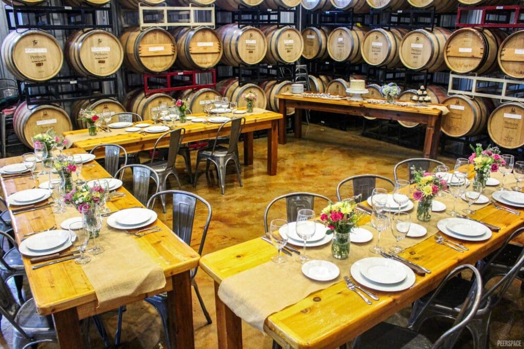 Tables are set with burlap and flowers in a cask hall