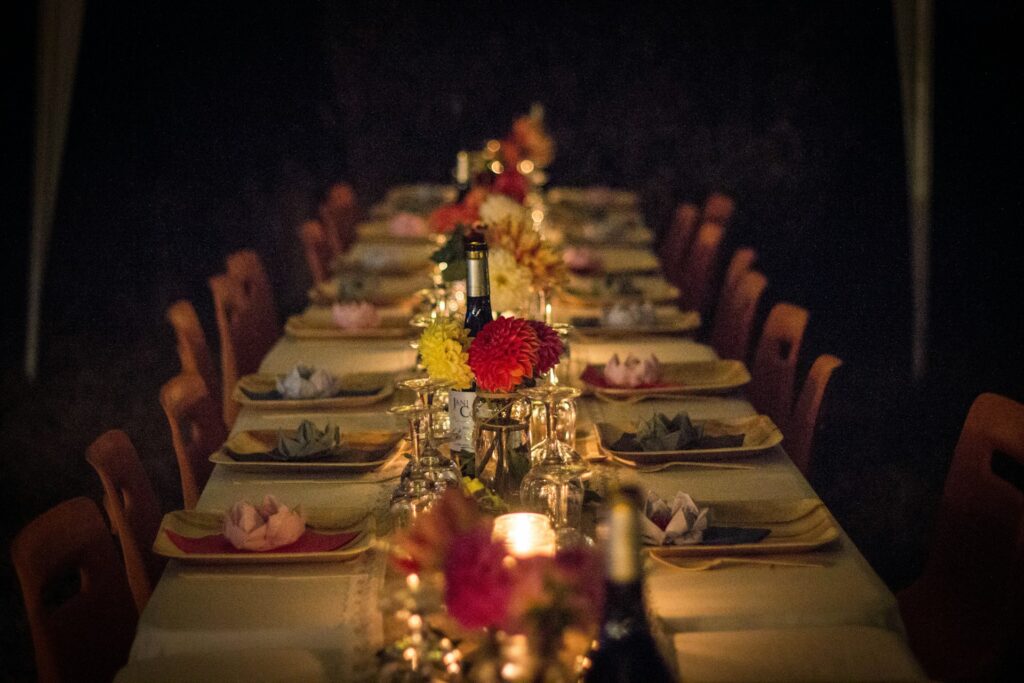 Long Friendsgiving dinner party table with place settings and floral arrangements