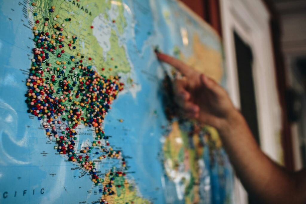 hand pointing to a map studded with pins