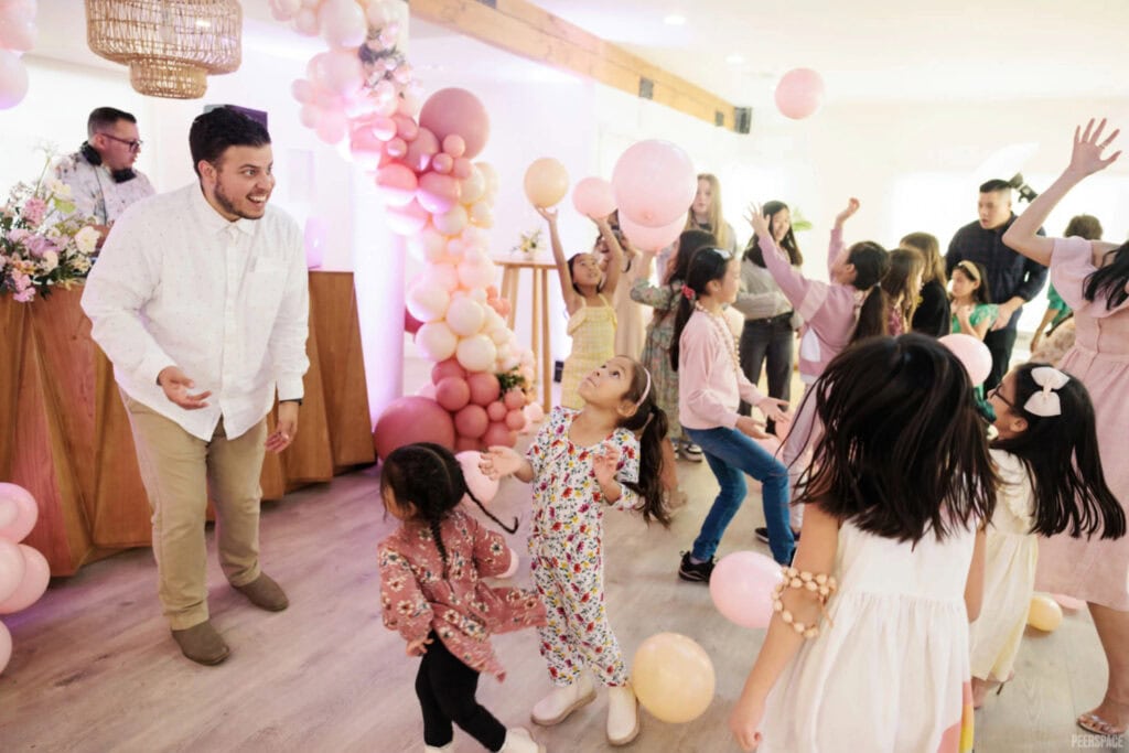 Kids play on dancefloor surrounded by pink balloons.