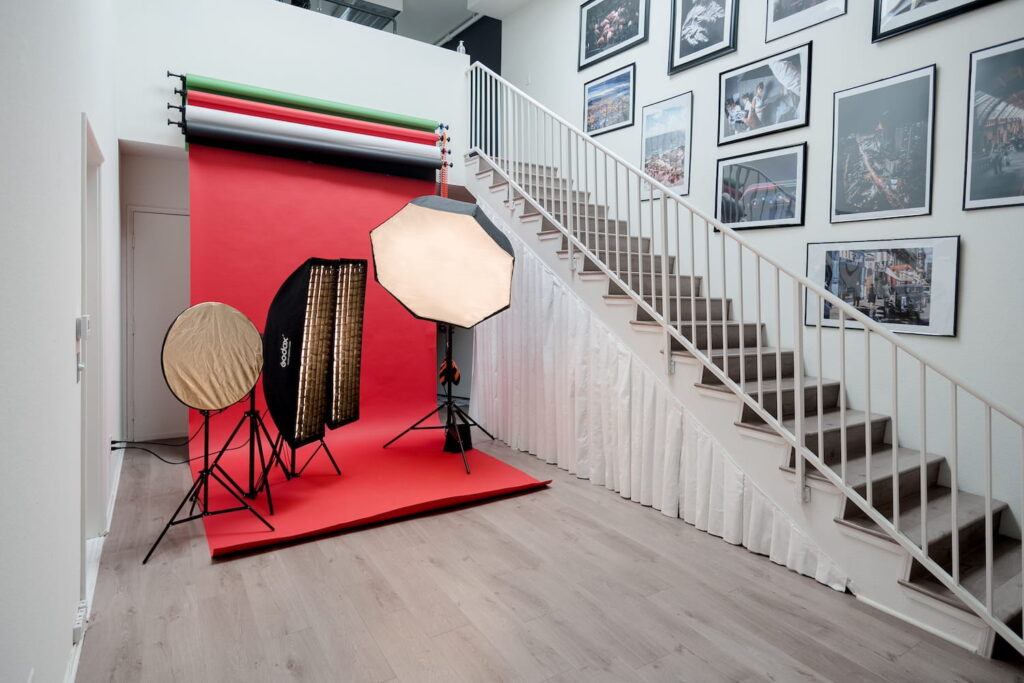 Studio space with differently colored backdrops, large lights and a stairwell with pictures on the walls