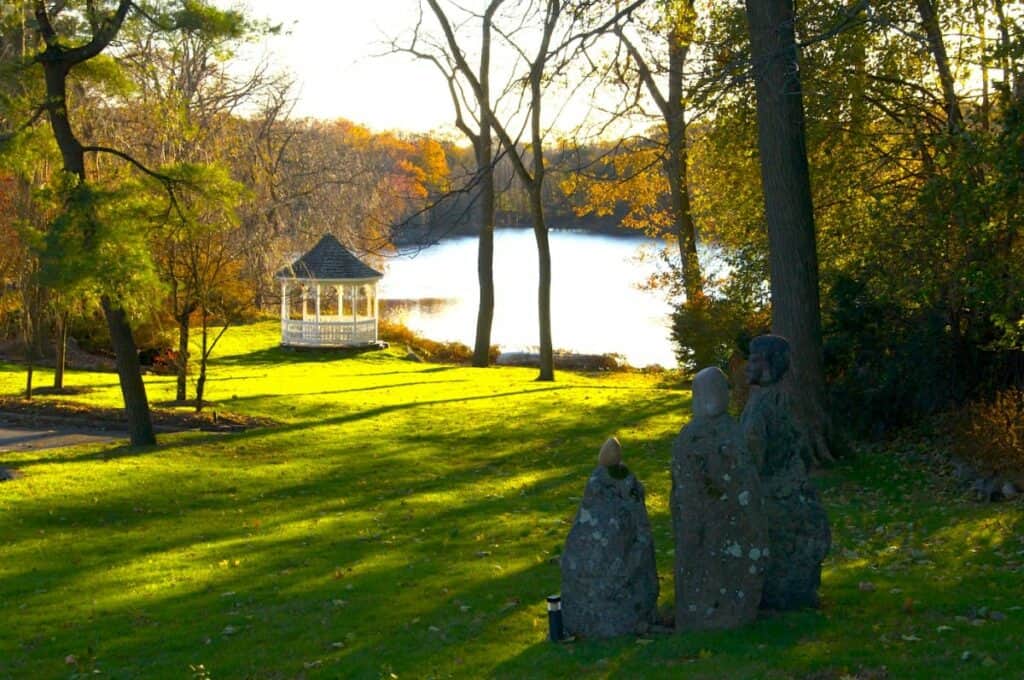 A gazebo next to a lake surrounded by trees
