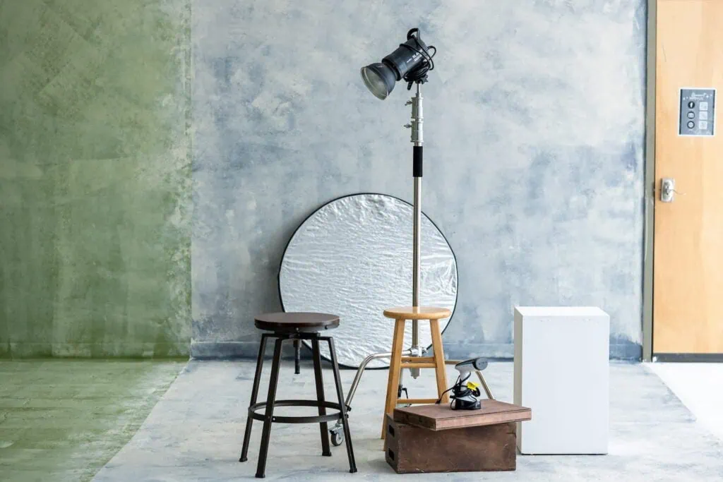Two stools, a steamer, reflectors, and lighting in a multi-colored photo studio