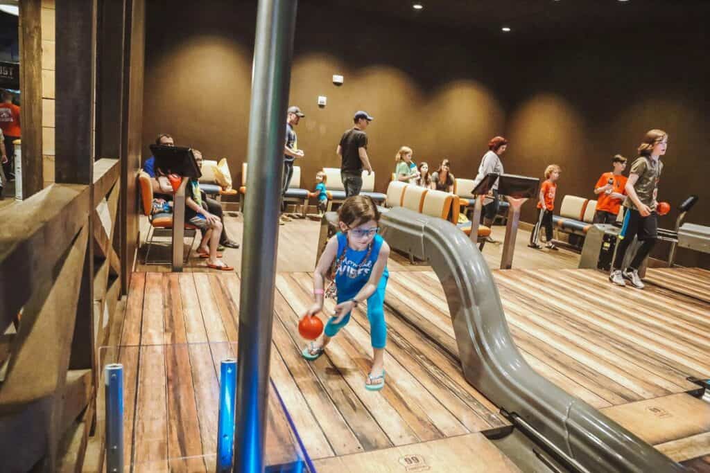 a little girl bowling at an alley