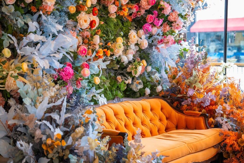 orange sofa surrounded by colorful flowers