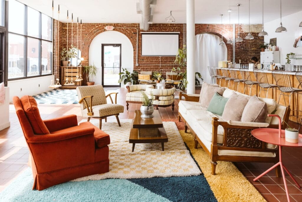 A bright event space in downtown Kansas City with plush chairs and couches, a long bar, exposed brick accents and wooden swings hanging from the ceiling
