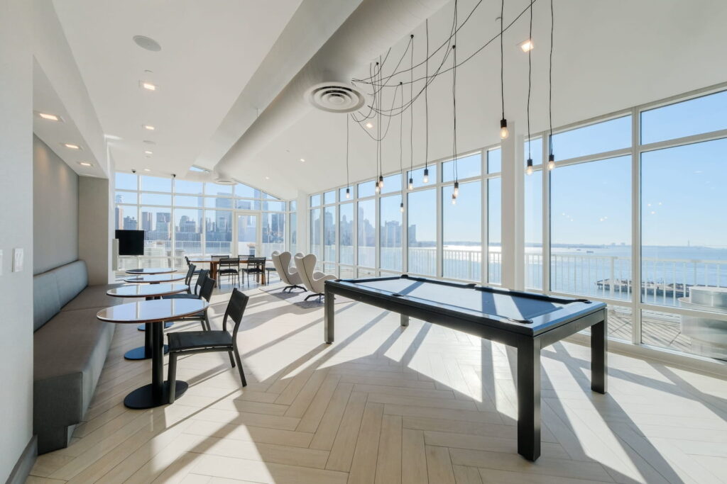 Sun-drenched lounge space with city views, a pool table, and multiple seating areas