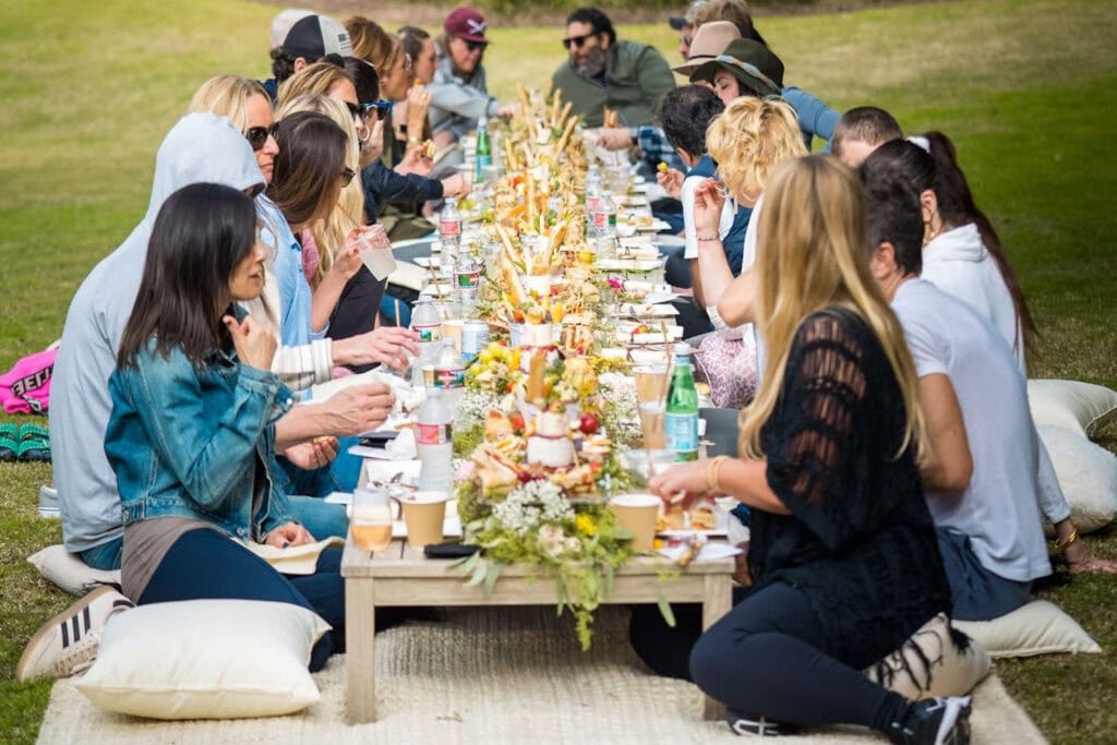 A group of people sit at a low-lying table enjoying a meal