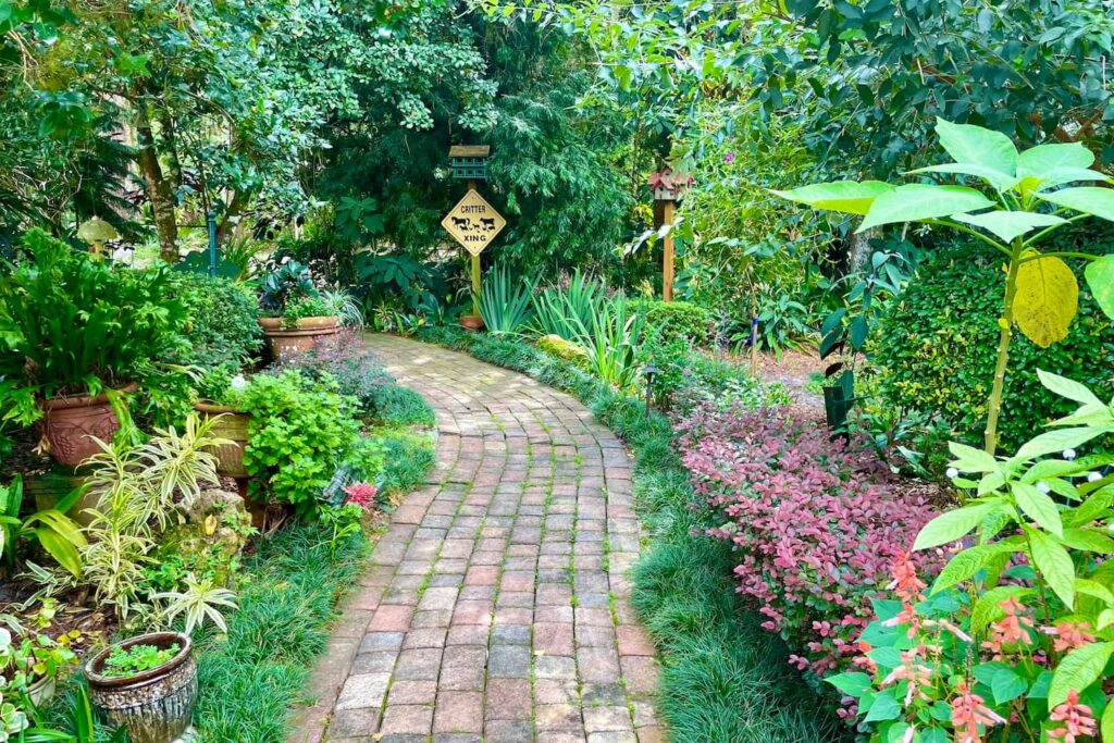 A lush brick walkway lined with all different types of greenery