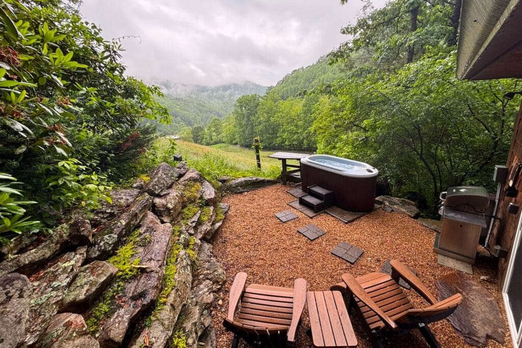 A small hot tub sits on a patio by a cabin on a large, luxury farm