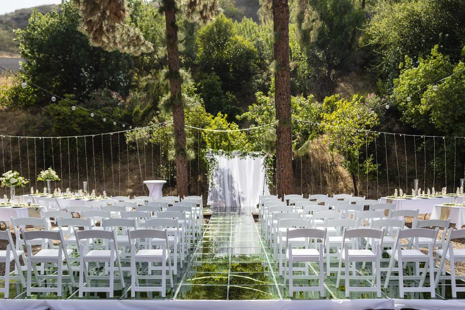 Luxury wedding ceremony setup with glass aisle and draped altar
